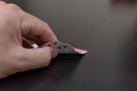 Téléchargez les photos : Poche (paire) d'as dans un jeu de poker avec une main et une table noire - en image libre de droit