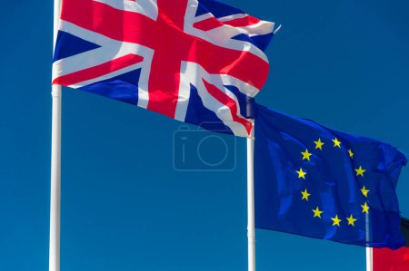 Téléchargez les photos : "Drapeau britannique et drapeau européen agitant contre le ciel bleu à Wimere" - en image libre de droit