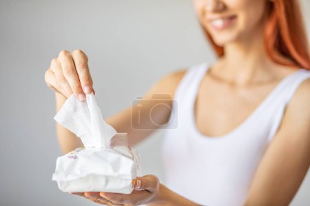 Téléchargez les photos : Lingettes humides : femme prendre une lingette de l'emballage pour le nettoyage - en image libre de droit
