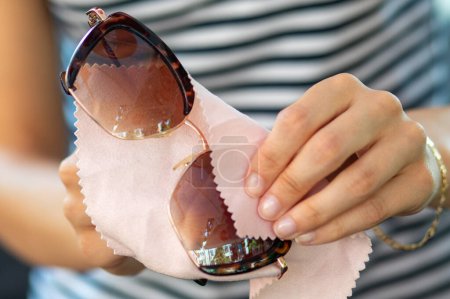 Foto de Mujer manos limpieza gafas de sol protectoras con micro fibra toallita - Imagen libre de derechos