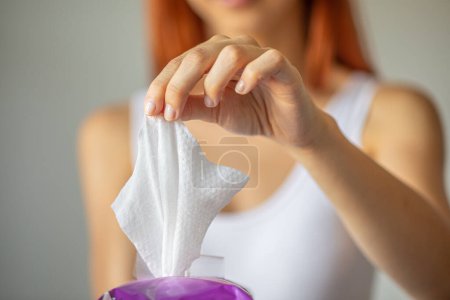 Téléchargez les photos : Lingettes humides : femme prendre une lingette de l'emballage pour le nettoyage - en image libre de droit