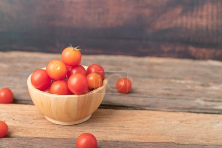 Photo for "Cherry tomatoes in a wood bowl place on the wooden table" - Royalty Free Image