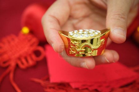 Téléchargez les photos : Lingot chinois en or à la main sur fond, gros plan - en image libre de droit