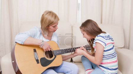 Photo for Mother and daughter playing guitar at home - Royalty Free Image
