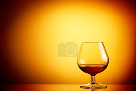 Photo for Glass of cognac on orange background - Royalty Free Image