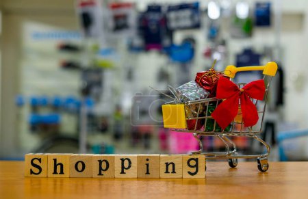 Téléchargez les photos : Petit panier et cadeaux avec le mot "shopping" sur la table. - en image libre de droit