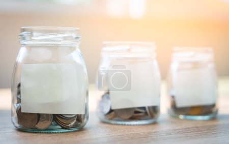Téléchargez les photos : "Money savings concepts. Put coins in glass bottles with paper la" - en image libre de droit