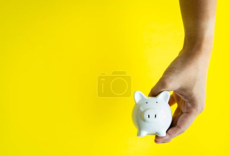 Photo for "Money savings concepts. The piggy bank in hand is giving for sav" - Royalty Free Image