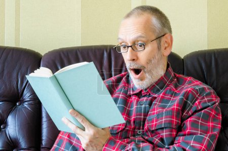Téléchargez les photos : Homme âgé étonné de lire un livre - en image libre de droit