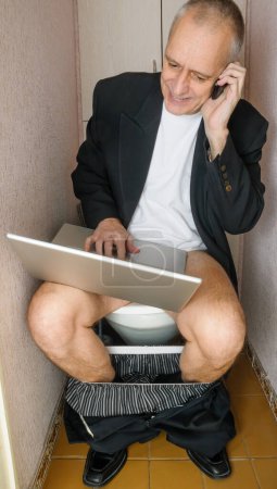 Foto de Empresario adulto adicto al trabajo en el baño - Imagen libre de derechos