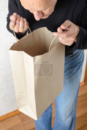 Téléchargez les photos : Homme regardant à l'intérieur d'un sac en papier - en image libre de droit