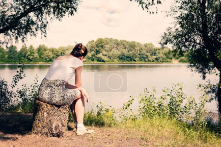 Téléchargez les photos : Femme assise près de la rivière - en image libre de droit