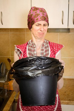 Téléchargez les photos : "Femme regardant à l'intérieur d'une poubelle" - en image libre de droit
