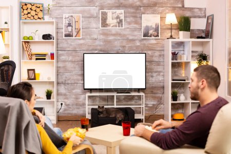 Foto de Pareja mirando la pantalla de TV aislada en la acogedora sala de estar - Imagen libre de derechos