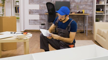 Téléchargez les photos : Travailleur masculin portant des lunettes de protection avant l'assemblage des meubles - en image libre de droit