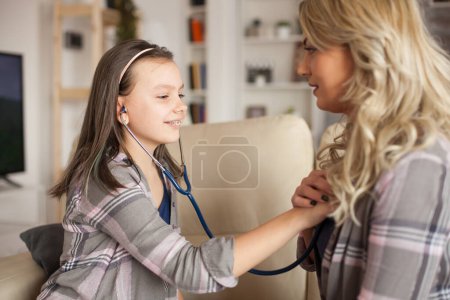 Photo for Female doctor teaching her little girl how to use stethoscope - Royalty Free Image