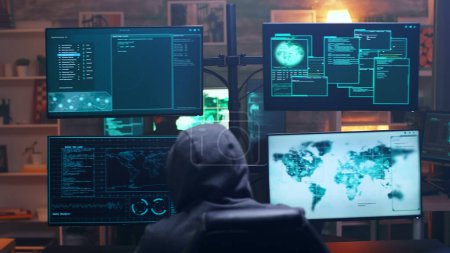 Foto de Vista posterior del cyber terrorista encapuchado usando super ordenador - Imagen libre de derechos