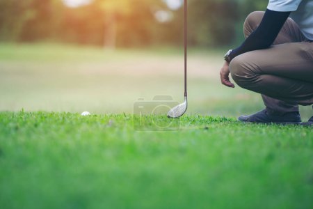 Gracz w golfa sprawdzić linię do umieszczenia piłki golfowej na zielonej trawie
