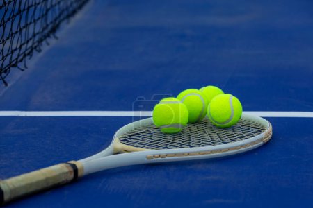 Foto de Raqueta de tenis de primer plano y bolas colocadas en el campo azul - Imagen libre de derechos