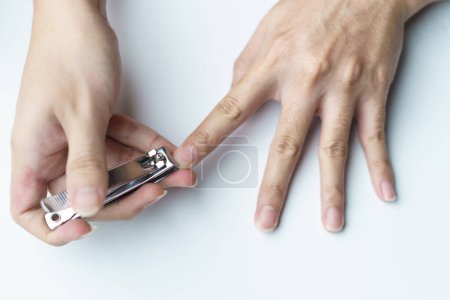 Téléchargez les photos : Un homme utilisant une tondeuse à ongles lui coupant les ongles. fond blanc - en image libre de droit