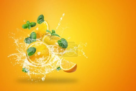 Foto de Salpicaduras de agua en las naranjas frescas en rodajas de fruta sobre fondo naranja - Imagen libre de derechos