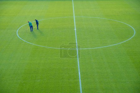 Téléchargez les photos : Ajuste manuellement la pelouse après un match de football - en image libre de droit