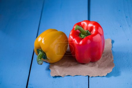 Photo for Yellow pepper and red pepper on blue wooden table - Royalty Free Image