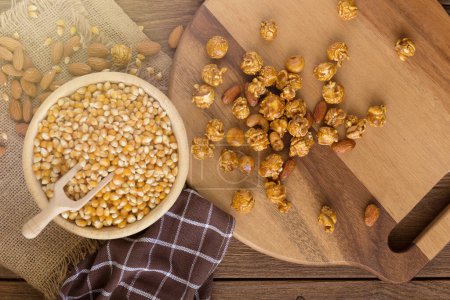 Foto de Corn kernels in wooden plates and popcorn with Caramel and almonds - Imagen libre de derechos