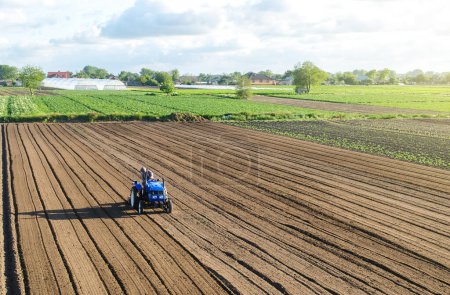 Photo for A farmer on a tractor processes a farm field. Farming and agriculture. Preparing the land for a new crop planting. Loosening the surface, cultivating soil for further planting. Work on the ground - Royalty Free Image