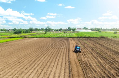 Photo for Farmer on tractor loosens and grinds the soil. Preparing the land for a new crop planting. Loosening the surface, cultivating the land. Farming and agriculture. agricultural sector of the economy - Royalty Free Image