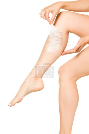 Photo for Woman touching her beautiful legs with feather on white backgroud - Royalty Free Image