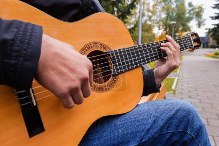 Photo for Musician playing a six string guitar in the park - Royalty Free Image