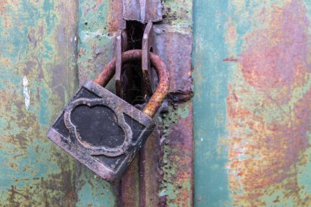 Téléchargez les photos : Vieux cadenas en acier verrouille solidement la porte du hangar - en image libre de droit