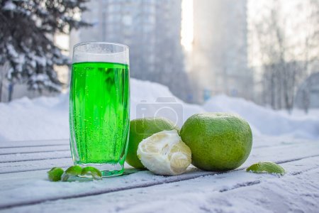 Téléchargez les photos : Les jus de fruits frais dans un verre et les agrumes se tiennent à l'extérieur un matin d'hiver. Mode de vie sain et regain d'énergie le matin - en image libre de droit