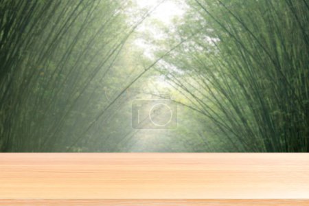 Foto de Pisos de mesa de madera vacíos sobre fondo blurred bambú verde suave, tablero de mesa de madera arco arqueado frente vacío árbol de bambú desenfoque naturaleza, tablón de madera en blanco en el árbol de bambú para maqueta de productos de exhibición - Imagen libre de derechos
