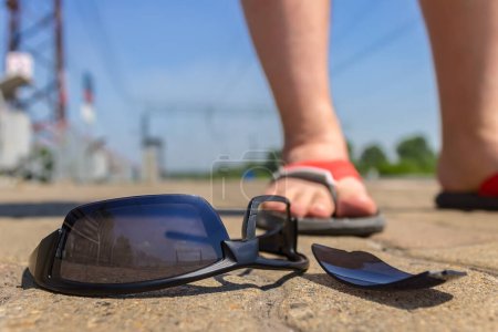Photo for Black glasses lie on the road near the young boy in sandals - Royalty Free Image