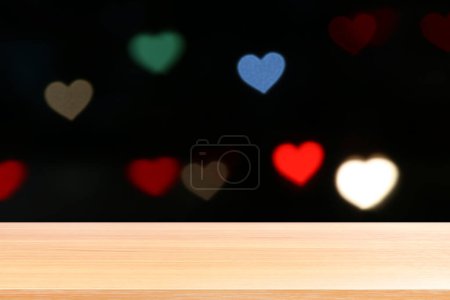 Téléchargez les photos : "planche de bois sur l'éclairage en forme de coeur coloré fond noir bokeh, planchers de table en bois vides sur fond bokeh lumière de nuit en forme de coeur multi couleur, planche de table en bois vide sur bokeh lumière en forme de coeur" - en image libre de droit