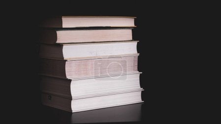 Photo for High messy stack of books on a black background with space for text message. - Royalty Free Image