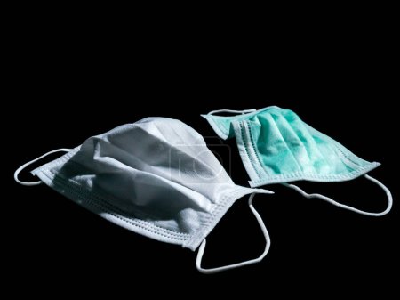 Téléchargez les photos : "Utilisé blanc et vert masques chirurgicaux placer sur fond noir." - en image libre de droit