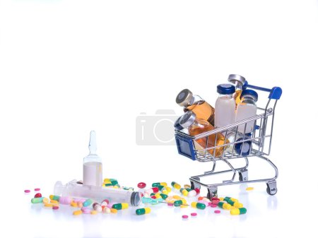 Foto de "medical vials in shopping cart, syringe, sterile water and tablets on white background." - Imagen libre de derechos