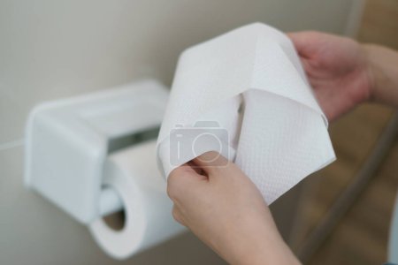 Photo for Hand pulling a roll of toilet paper tissue. - Royalty Free Image