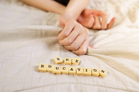 Photo for Woman hand sign orgasm on bed with scrabble board showing words - Royalty Free Image