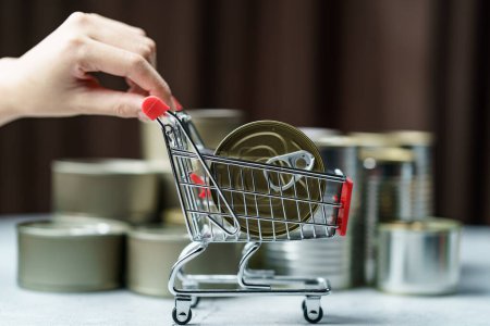 Foto de Canned food in shopping cart toy with Hand , group of Aluminium - Imagen libre de derechos