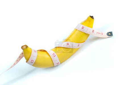 Téléchargez les photos : Une banane était enveloppée dans un ruban à mesurer. isolé - en image libre de droit