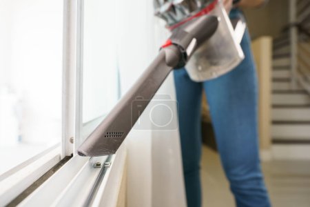 Téléchargez les photos : Femme utilisation aspirateur nettoyage fenêtre - en image libre de droit