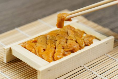 Foto de "Uni sushi en palillos. erizo de mar (uni sashimi). Sabroso concepto japonés de mariscos - Imagen libre de derechos