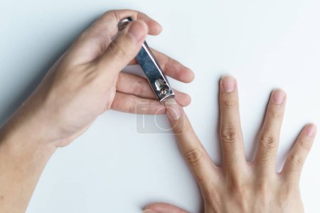 Téléchargez les photos : Un homme utilisant une tondeuse à ongles lui coupant les ongles. fond blanc - en image libre de droit