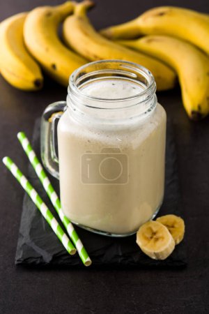 Photo for Banana smoothie in jar on black slate background - Royalty Free Image