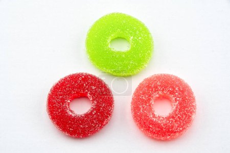 Téléchargez les photos : Trois bonbons gommeux enrobés de sucre rond sur fond blanc - en image libre de droit