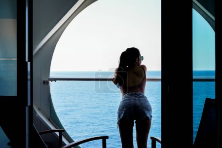 Téléchargez les photos : Femme relaxant sur bateau de croisière bénéficiant d'une vue sur l'océan depuis le balcon - en image libre de droit